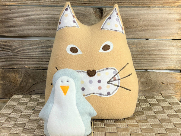 Beige cat pillow with brown and gray polka dot print and a gray penguin hot and cold pack
