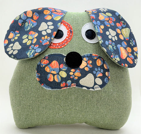 Sage green puppy pillow with a tie dye paw print face and floppy ears