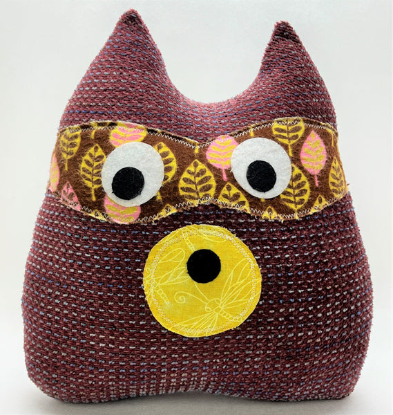 maroon raccoon pillow with yellow brown and pink accents