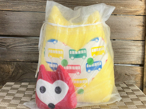Yellow fox pillow with primary color buses and a red fox hot and cold pack in an organza bag